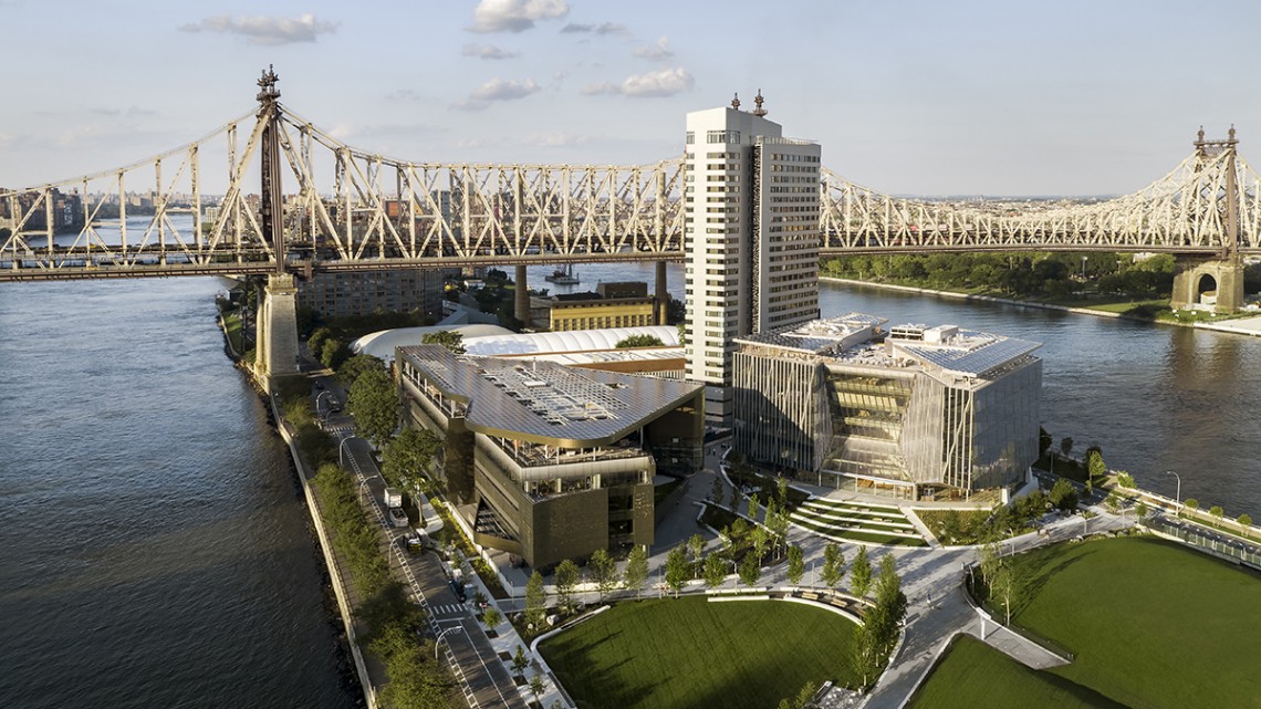 An aerial view of the Cornell Tech campus, showing the 59th Street Bridge over Roosevelt Island and the Great Lawn, in the foreground.