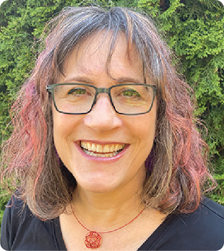 A color photo of a person smiling for a photo outdoors.