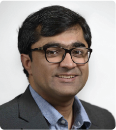 A color photo of a man with glasses, smiling for a photo.