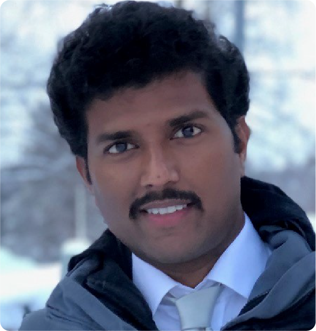 A color photo of a man smiling for a photo outside in the winter.