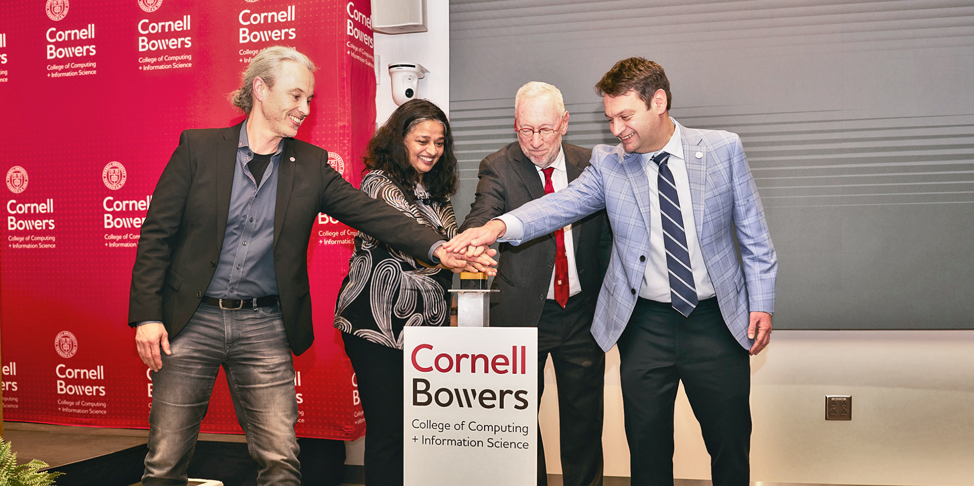 A color photo showing a group of people pushing a button at a building dedication.