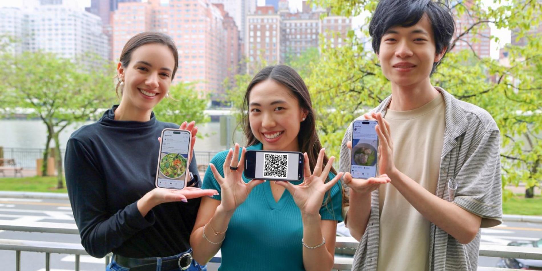 Three students looking at camera holding up phones to show their apps