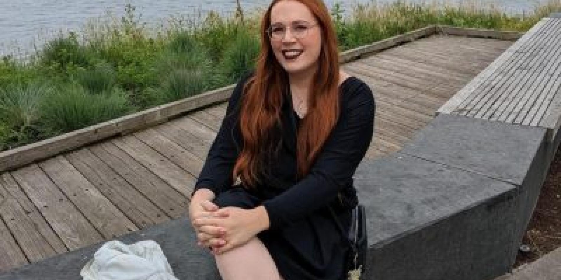 Aspeng Omapang sits next to a body of water in a black dress