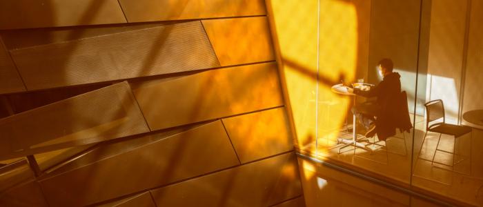 interior slanted orange walls in Gates Hall reflect sunlight on a person sitting at a high top table working
