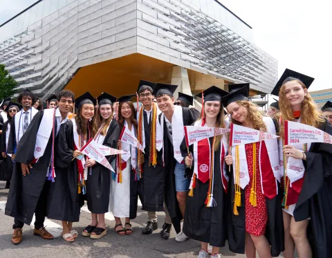 Group of students with pennants and in graduation regalia celebrating