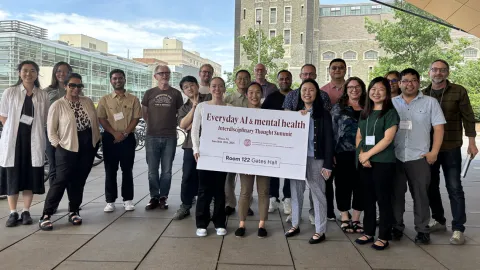 A color photo showing a group of people outside holding a large sign