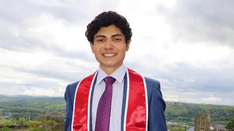 A color photo of a man smiling for a photo outdoors.