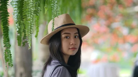 A color photo of a woman with dark hair wearing a hat.