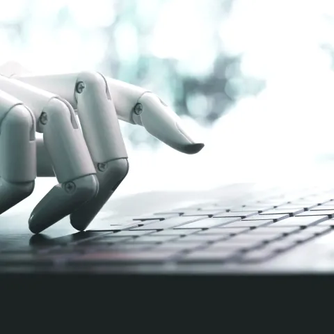 A white robotic hand types on a keyboard