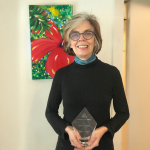 A color photo of a woman holding a glass award.