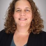 a women with brown curly hair wearing a dark jacket