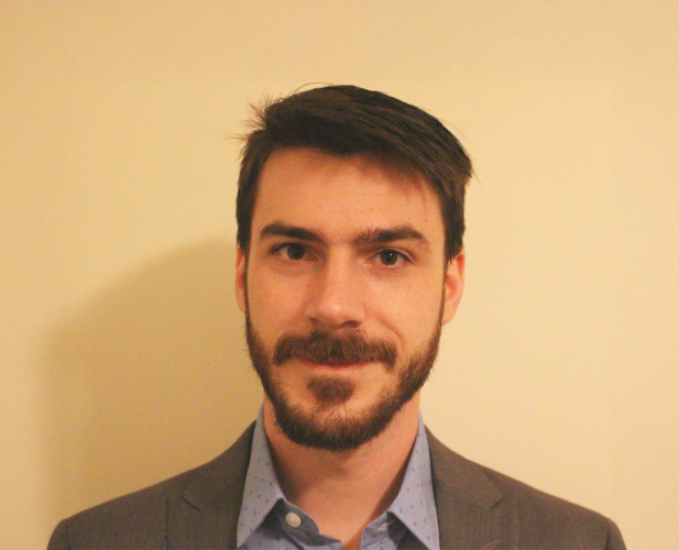 A color photo of Kirk Vanacore in front of a tan background