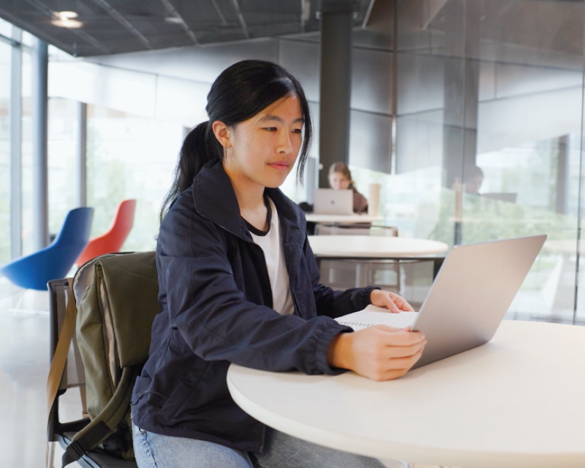 a young female Asian student works on a laptop