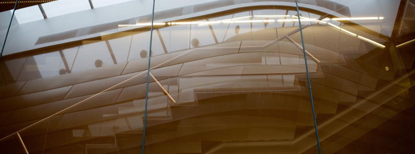 Architectural interior view of a modern staircase through reflective glass.