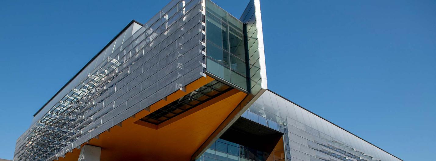 Modern angular glass and steel building against a clear blue sky.