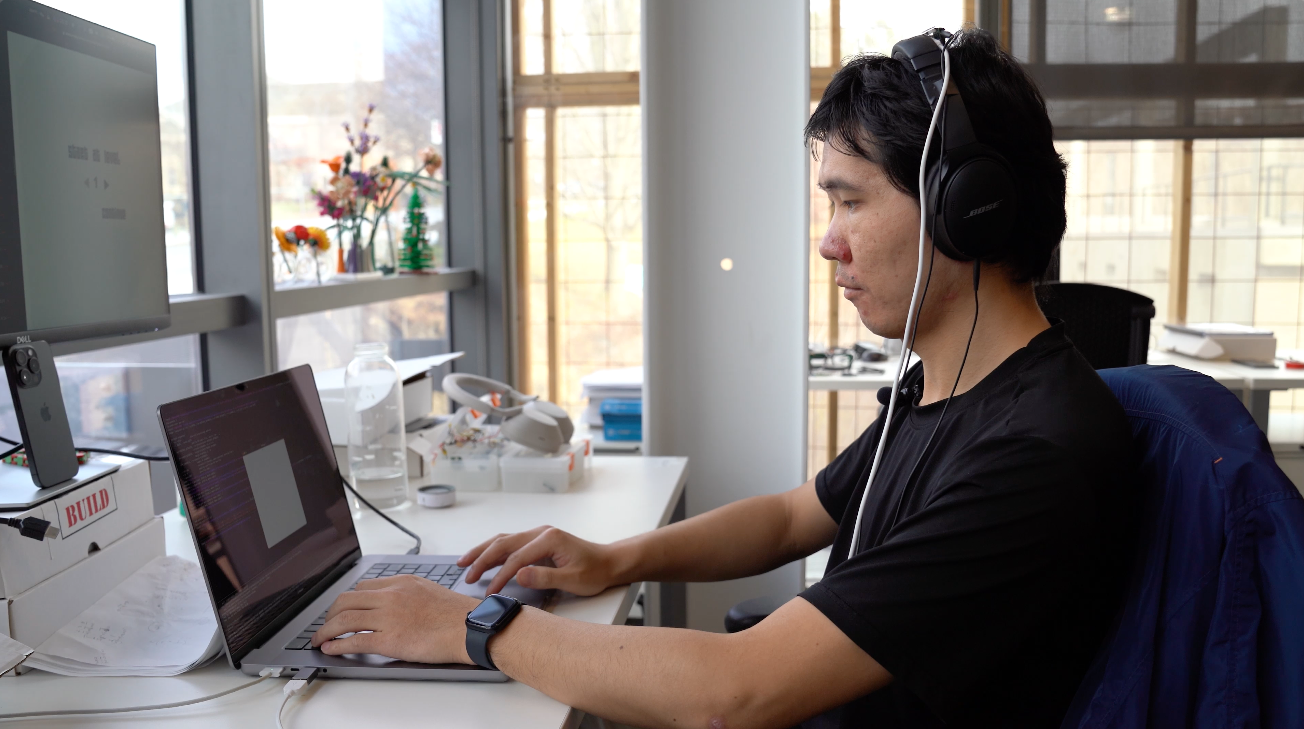 a student wears white wires and headphones and types on a laptop